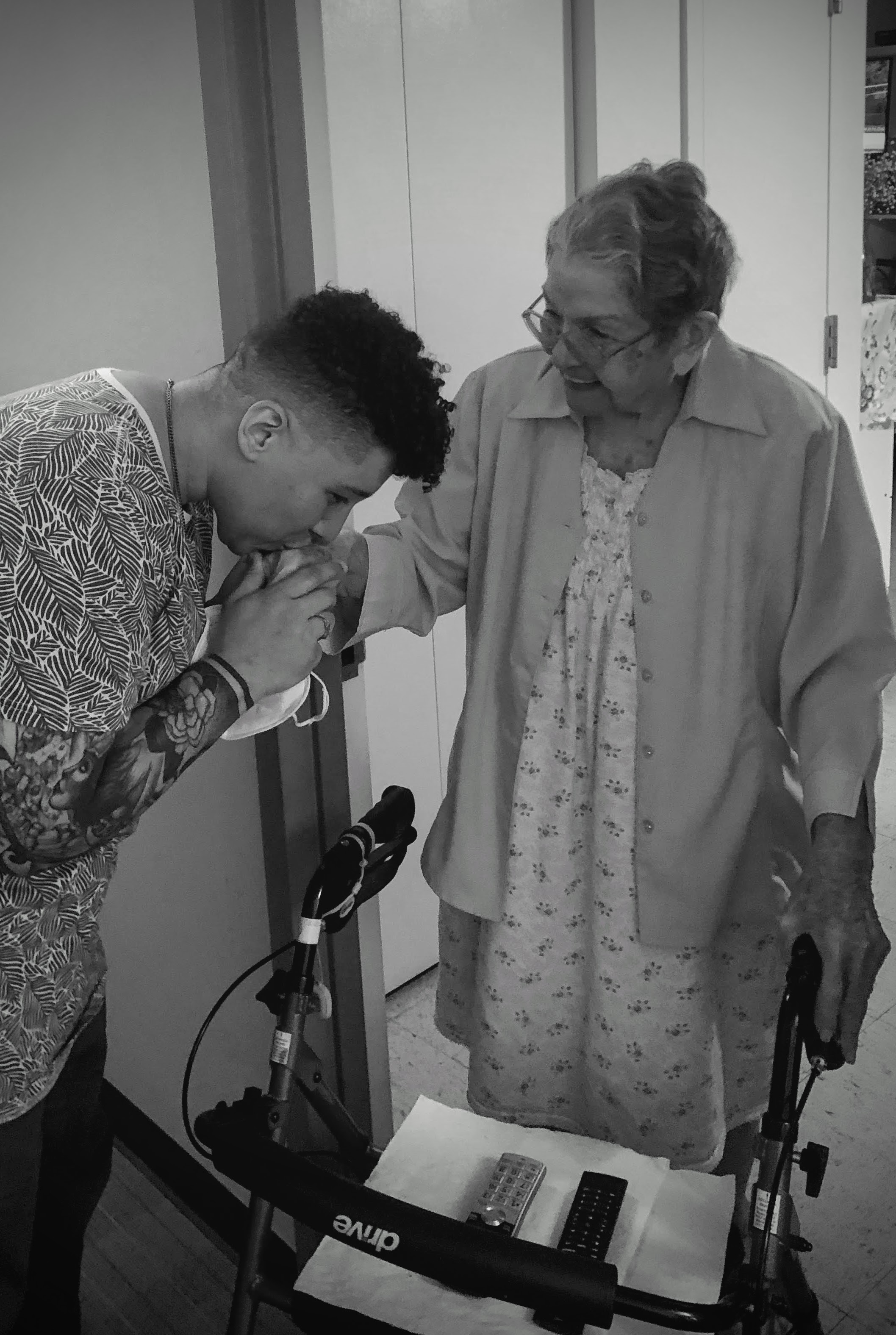 Keslie kissing their abuela's hand while she smiles broadly